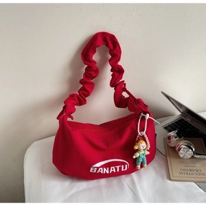 Détail du sac en toile rouge avec bandoulière plissée et pendentif perle cartoon