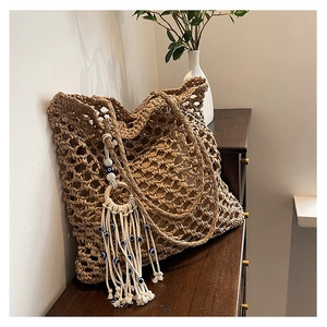 Detail of hollow woven tote bag featuring an evil eye tassel charm and inner pouch