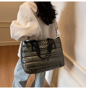 Détail d'un grand sac cabas matelassé vert foncé métallisé porté par un mannequin