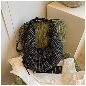 Detail of checkered crescent bag with adjustable strap on a chair in a lifestyle setting