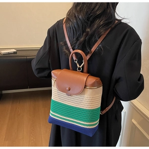 Detail view of woven color-block backpack with brown leather straps and metal zipper