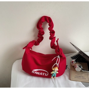 Détail du sac hobo rouge avec bandoulière plissée, breloque cartoon et logo BANATU
