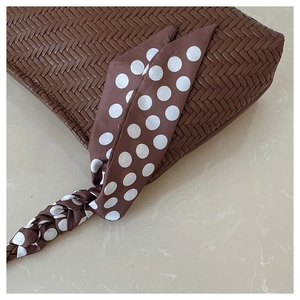 Detail of brown woven hobo bag with an elegant polka dot scarf handle decoration