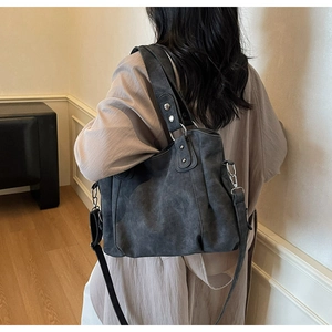 Détail d'un grand sac cabas gris foncé avec texture mate et bandoulière sur un modèle