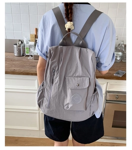 Rear view of a light purple waterproof nylon travel backpack with wide shoulder straps