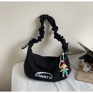 Détail du sac en toile plissé noir avec logo BANATU et charmante poupée accessoire