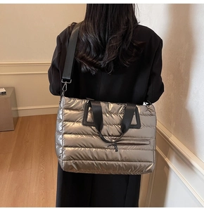 Détail d'un sac cabas argenté métallisé avec anses noires porté par un mannequin en intérieur
