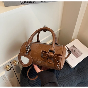 Detailed view of brown bow barrel bag with heart mirror charm and fine strap