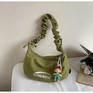 Vue détaillée du sac à bandoulière vert olive avec plis et un petit pendentif de dessin animé