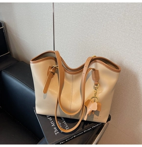 Detail of beige tote bag with brown trim and cute elephant leather charm on a chair
