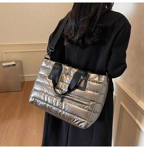 Détail macro d'un sac cabas argenté matelassé avec sangle noire et fini métallisé