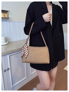 Detail of woven light brown shoulder bag with polka dot scarf on model in minimal interior