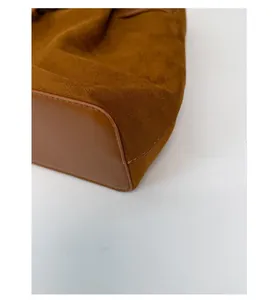 Detail view of reinforced bottom on brown suede tote bag with durable leather piping