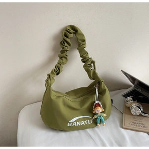 Détail du sac en nylon vert olive avec bandoulière plissée et charm de poupée mignon