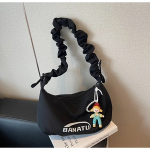 Détail d'un sac croissant noir plissé avec logo de marque et pendentif perle mignon
