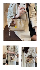 Détail du sac à main plissé beige avec poignées marron et pendentif smiley jaune