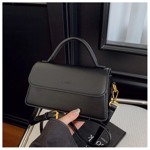 Detail of black matte shoulder bag with gold hardware and embossed logo on the flap