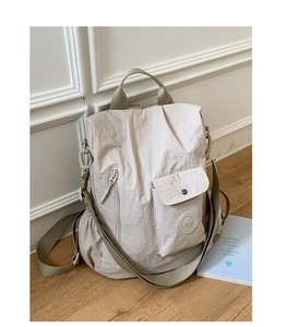 Close-up of beige waterproof nylon backpack with multiple pockets and top handle
