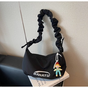 Détail du sac croissant en toile noire avec poignée plissée et charmante peluche