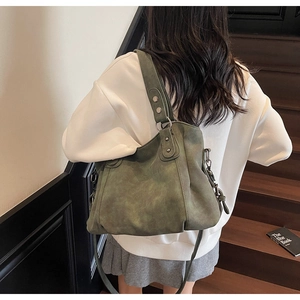 Détail d'un grand sac cabas vintage vert avec rivets porté à l'épaule par un mannequin