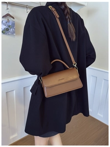 Detailed back view of a dark brown leather shoulder bag worn over a black blazer