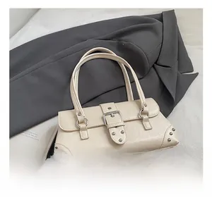 Detail der cremeweißen Kunstleder-Handtasche mit Silberschnallen auf grauem Blazer