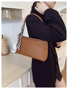 Close-up of woven brown underarm bag featuring a stylish polka dot silk scarf detail