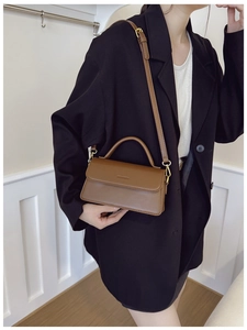 Detail view of brown matte leather shoulder bag with gold hardware and embossed logo