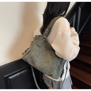 Gros plan du sac cabas en cuir mat vert mousse avec rivets et bandoulière réglable