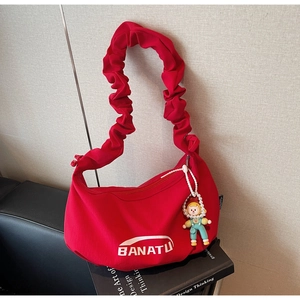 Détail du sac rouge en toile avec logo BANATU et breloque poupée en perles
