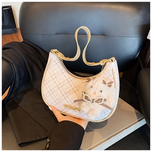 Detail of checkered hobo bag with leather strap and plush rabbit charm on black background