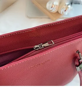 Detail view of deep red pebbled leather tote with smooth metal zipper and silver puller