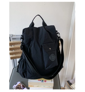 Close-up of black nylon multi-functional bag with front pocket on a wooden chair