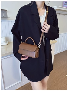 Detailed close-up of brown faux leather shoulder bag with metallic hooks and top handle