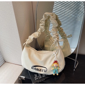 Détail d'un sac hobo crème avec poignées plissées, logo et breloque en perle