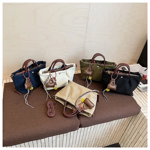 Détails de cinq sacs cabas en nylon colorés avec anses en cuir et mini pendentifs
