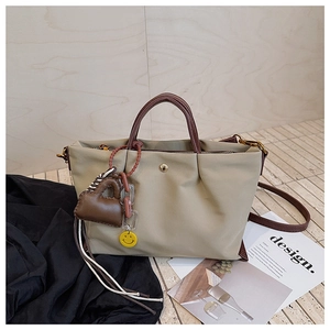 Détail du sac plissé vert olive en toile avec anses marron et charm de sac miniature