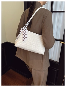 Detail of white woven hobo bag with textured pattern and decorative polka dot silk scarf