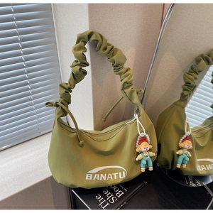 Détail du sac vert avocat avec bandoulière plissée et breloque poupée de dessin animé