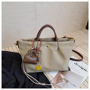 Gros plan détaillé du sac en nylon kaki avec breloque cœur en cuir et pendentif smiley