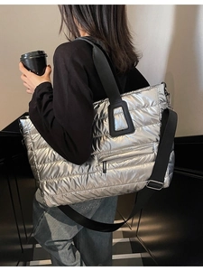 Sac fourre-tout matelassé argenté avec bandoulière noire porté par un mannequin