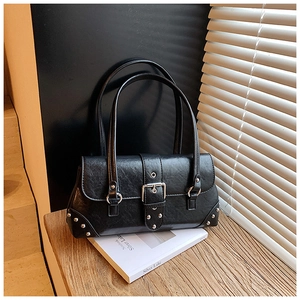 Nahaufnahme der schwarzen Retro-Ledertasche mit silbernen Nieten auf dem Holztisch