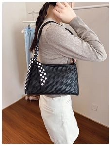 Detail of black woven shoulder bag with chic black and white polka dot scarf handle