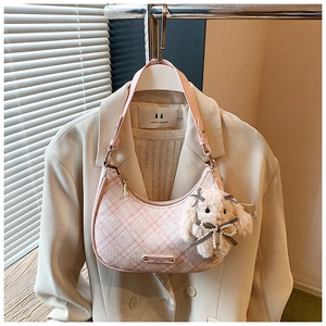 Pink checkered hobo bag with plush rabbit charm hanging on white suit and blazer