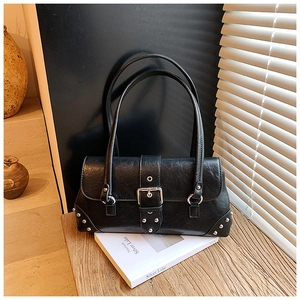 Nahaufnahme der schwarzen Retro-Achseltasche mit Silberschnallen und Nieten auf Holz