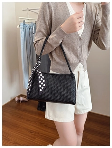 Close-up of black woven leather handbag detail with decorative polka dot silk scarf accessory