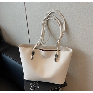Detailed macro of white pebbled leather tote bag with silver hardware on a chair