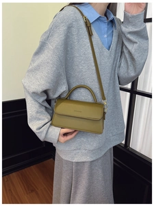 Olive green leather bag shown on model highlighting size and crossbody strap detail