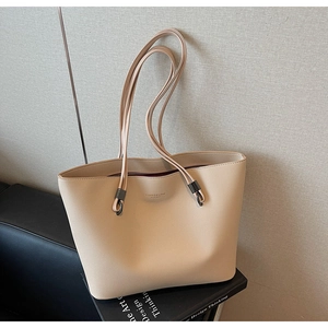 Detail of beige lychee grain leather tote bag with thin straps and embossed lettering