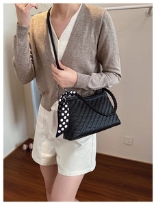Detail of black woven shoulder bag with V-shaped texture and polka dot silk scarf